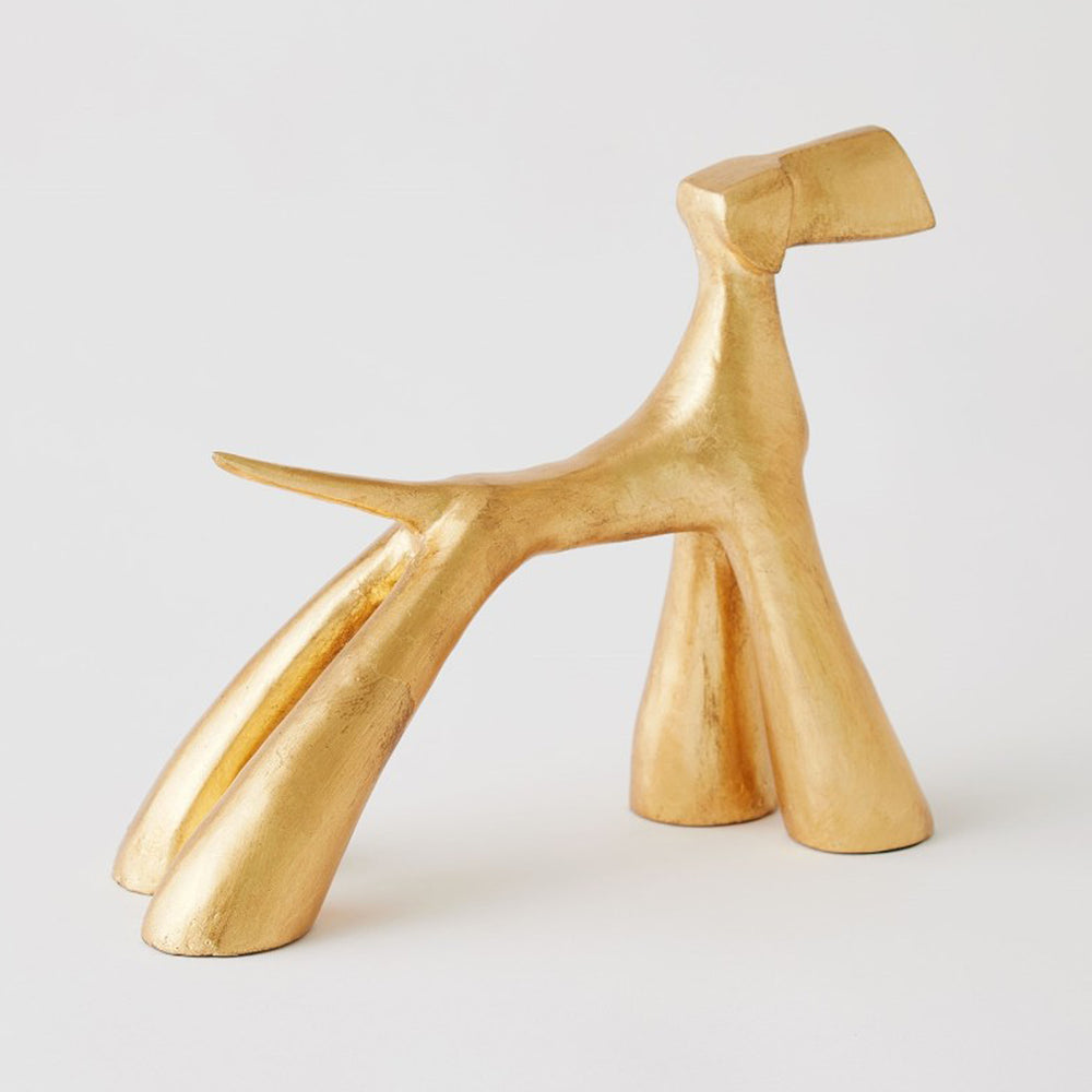 Gold abstract sculpture on a light gray background. Gold Leaf Sculpture Doggo G District Home