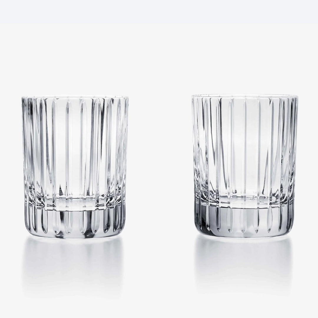 Two clear glass tumblers with vertical ridges on a white background. Baccarat Set of 2 Extra Large Harmonie Tumbler District Home