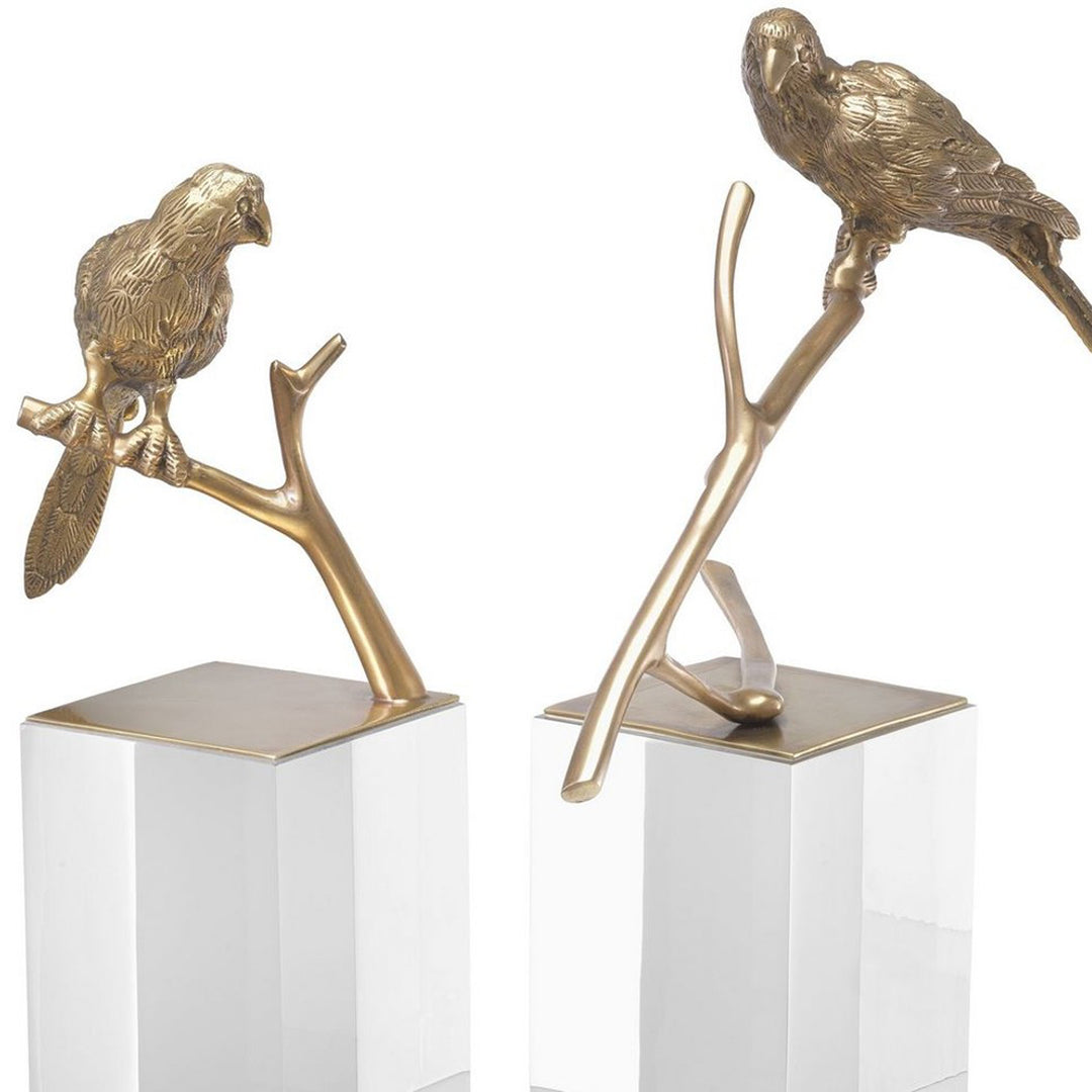 Two gold parrot sculptures on branches with clear bases on a white background. Decorative Sculpture Tweet by District Home