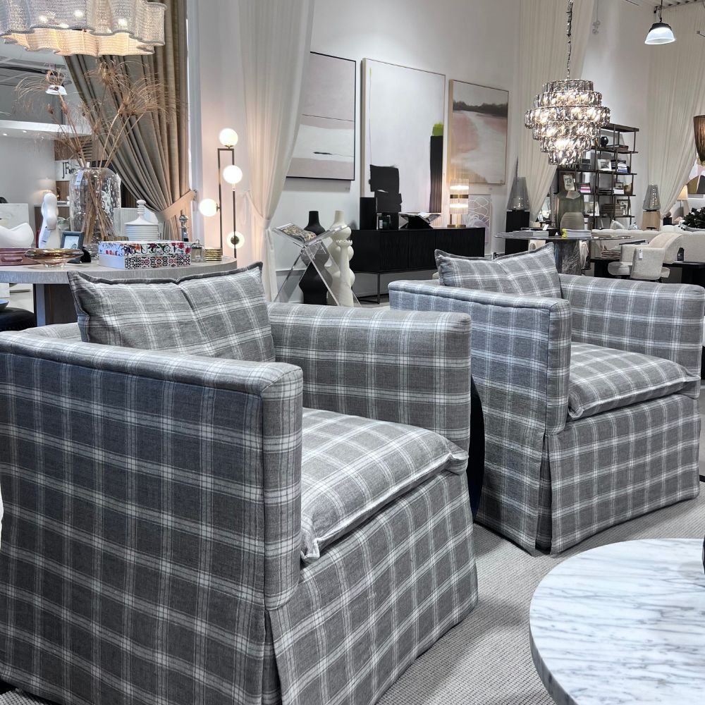 Gray plaid armchairs in a showroom setting with decor elements. Lisbeth Accent Chair by District Home