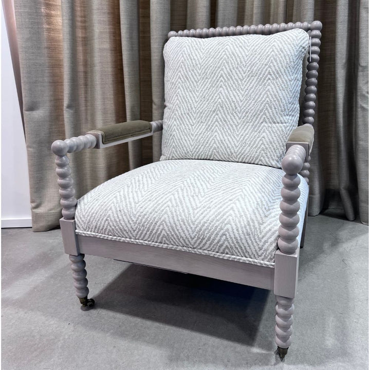 Gray armchair with textured cushion against a neutral curtain background. Keystone Accent Chair by District Home